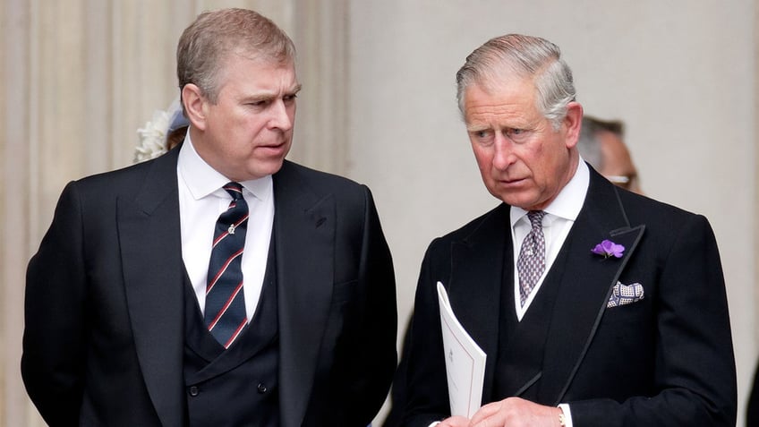 Prince Andrew in a dark suit next to King Charles speaking sternly to him.