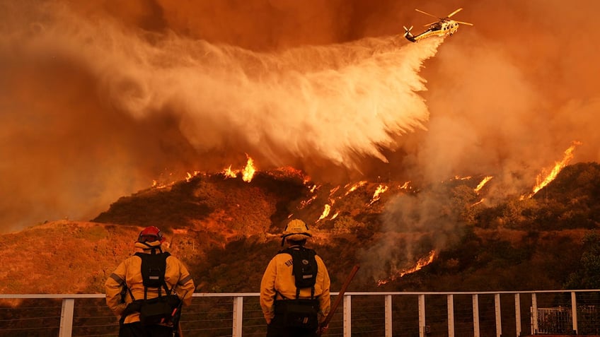 Firefighters watch as water drops