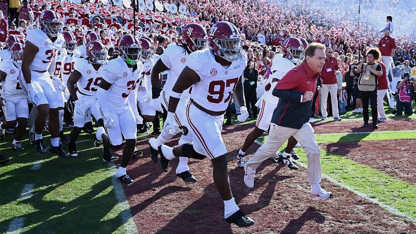 Nick Saban leads his team onto the field