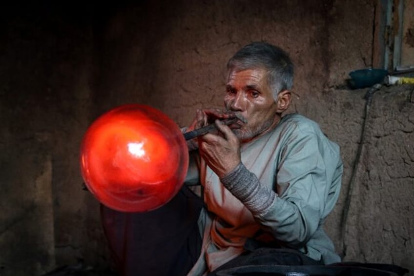 Afghan glassblower Ghulam Sakhi Saifi crafts glassware at his traditional workshop in the