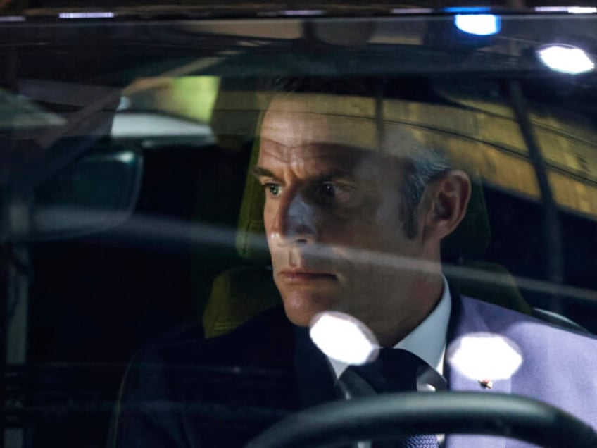 Spotlights are reflected in the windscreen as French President Emmanuel Macron sits in a c