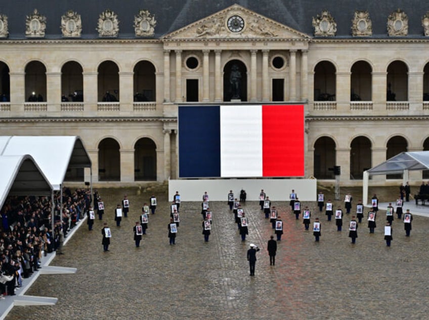 PARIS, FRANCE - FEBRUARY 7: French President Emmanuel Macron (C) stands in front of members of the French Republican Guard (Garde Republicaine) holding portraits of the 42 French and French-Israeli citizens killed,during on February 7, 2024 in Paris, France. The ceremony pays tribute to the 42 French and French-Israeli citizens …