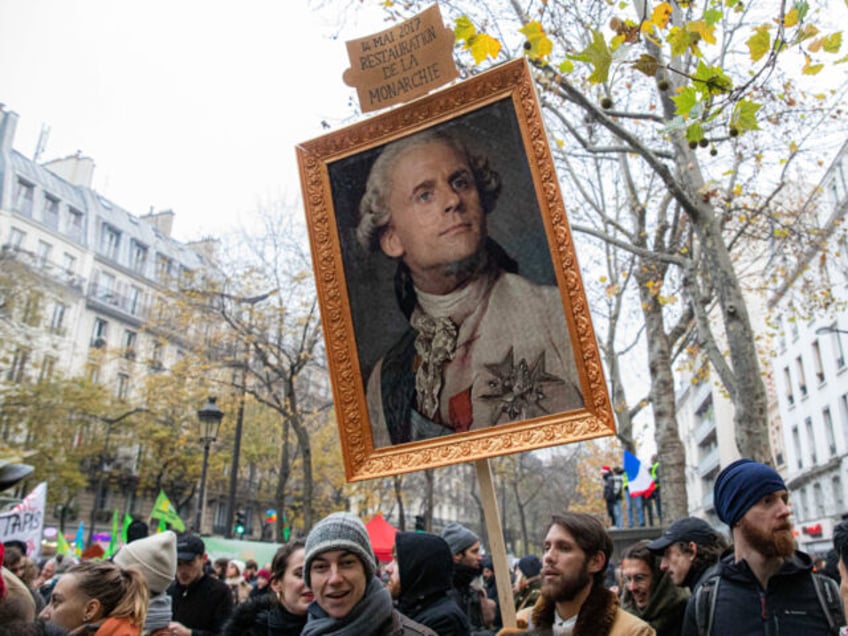 A protester holds a caricature painting depicting France's President Emmanuel Macron as a
