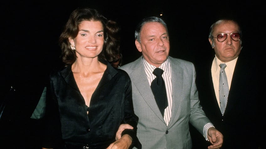 Frank Sinatra walking in between Jackie O and Jilly Rizzo.