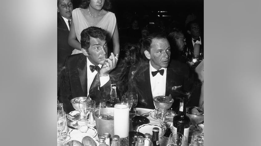 Frank Sinatra and Dean Martin looking concerned at a party.