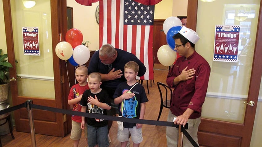 Group of people saying the Pledge of Allegiance in an ice cream store.