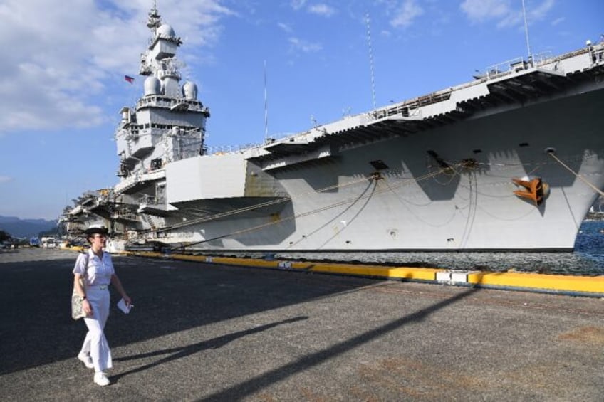 A sailor walks past the French aircraft carrier Charles de Gaulle, berthed at the former U