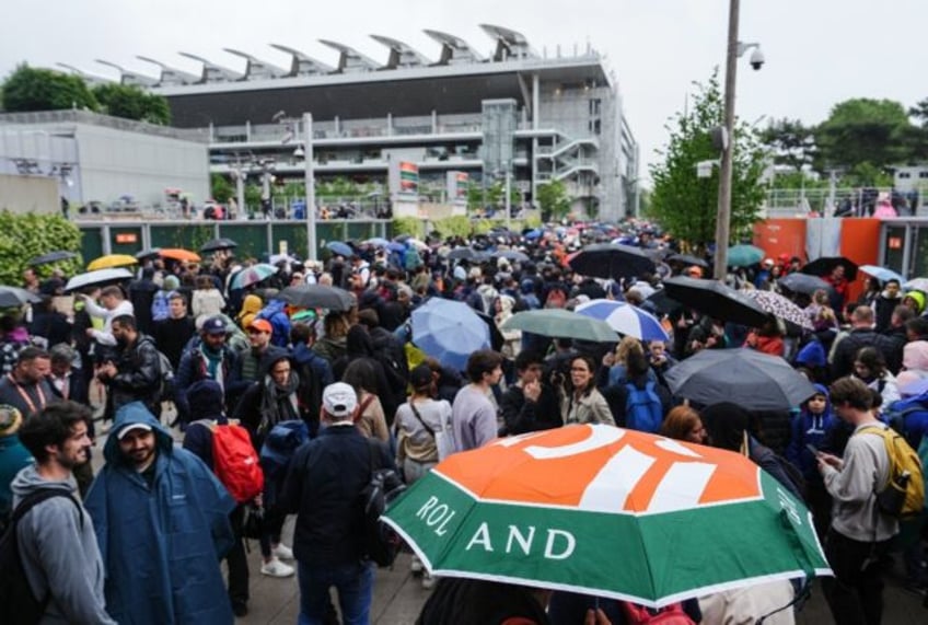 Rain pain: Spectators fill their time waiting for the rain to stop on Wednesday as play on