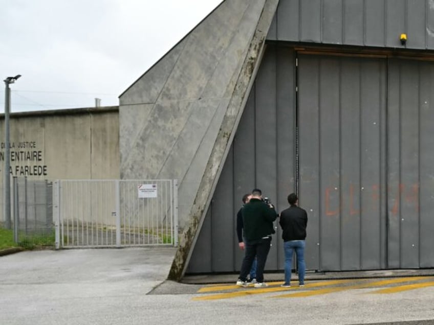 Journalists stand next to bullet impacts and letters "DDFM" spray-painted on a door of the