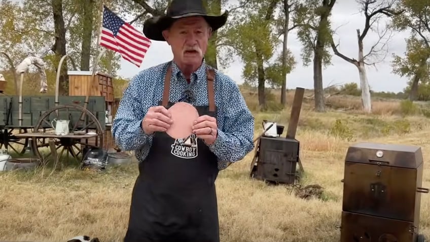 Kent Rollins holds a slice of bologna during one of his "Cowboy Cooking" shows on YouTube.