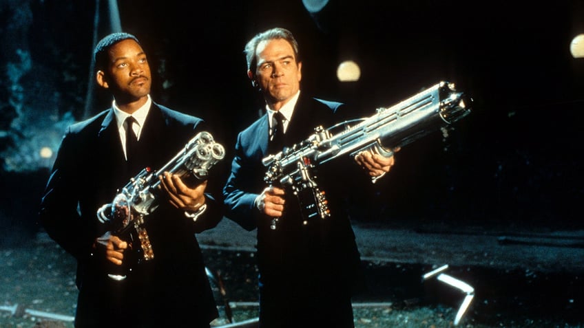 Will Smith and Tommy Lee Jones in 'Men in Black' both wearing suits and holding large weapons