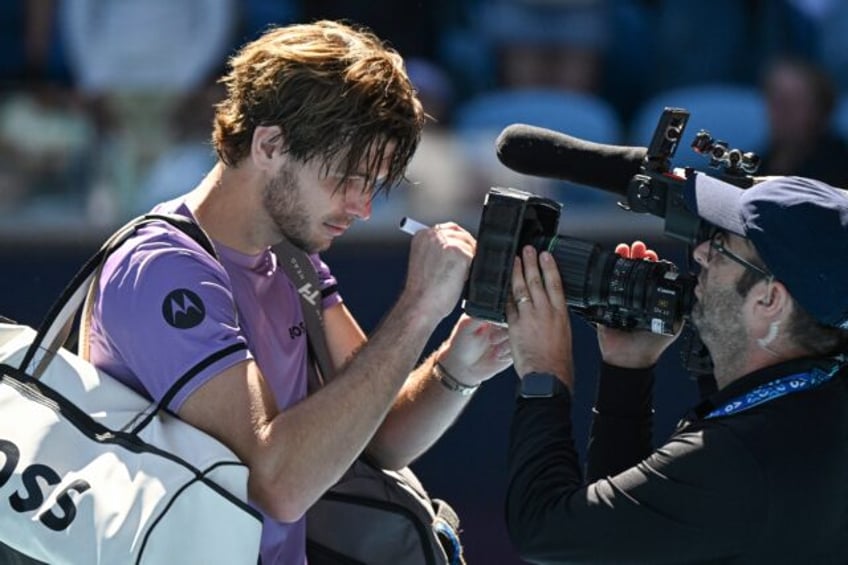 Taylor Fritz writes a message on a video camera lens after his Australian Open second roun