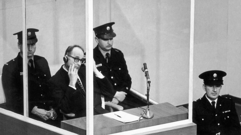 Adolf Eichmann, in a bullet-proof cabin, puts on earphones to hear the reading of the act of accusation against him on Dec. 17, 1961.