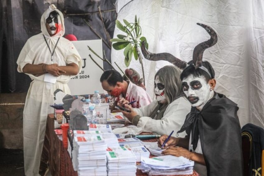 Staff members wearing horror themed costumes work at a polling station during Indonesia’