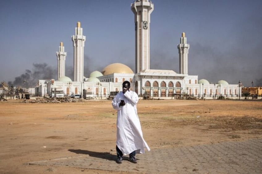 A man covers his face to protect from tear gas as protesters clashed with police in Dakar