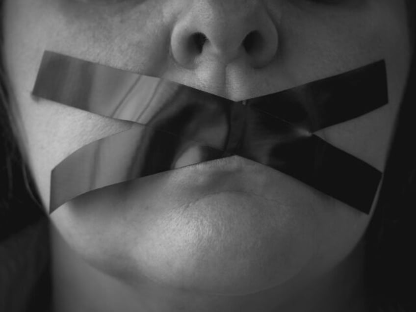 Portrait of a woman with an x of adhesive tape covering her mouth - stock photo/Getty Imag