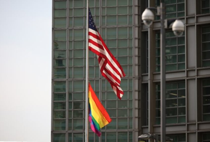 The rainbow Pride flag is seen hanging below the US flag outside the US embassy in Moscow