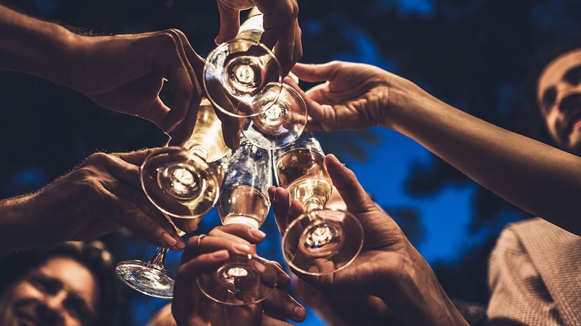 Close up of group of unrecognizable people toasting with champagne on a night party.