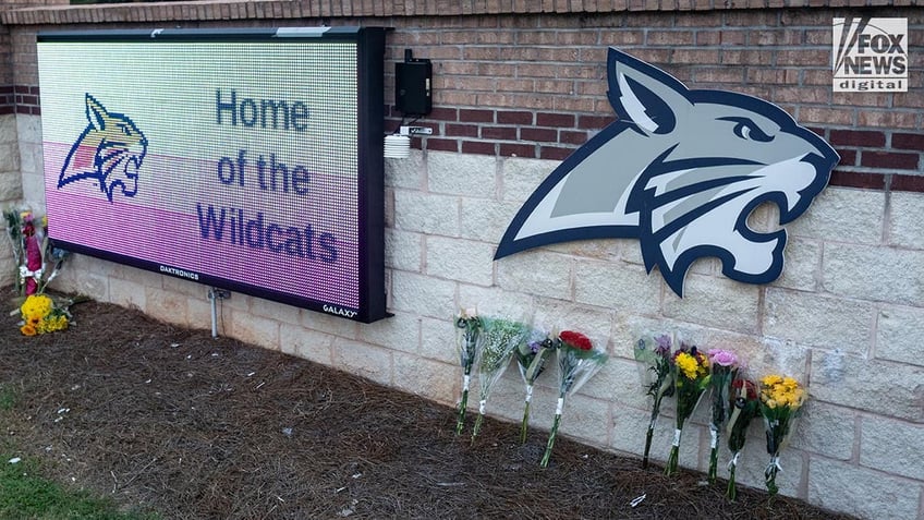 Flowers sit against the Apalachee High School sign