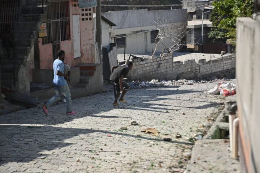 A man runs with a machete in his hand down a street in the Solino district of the Haitian capital Port-au-Prince, January 18, 2024