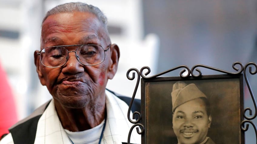 World War II veteran Lawrence Brooks holds a photo of him taken in 1943, as he celebrated his 110th birthday at the National World War II Museum in New Orleans, Thursday, Sept. 12, 2019.