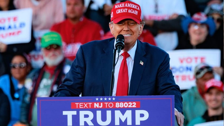 Former President Trump in red MAGA hat speaking at rally