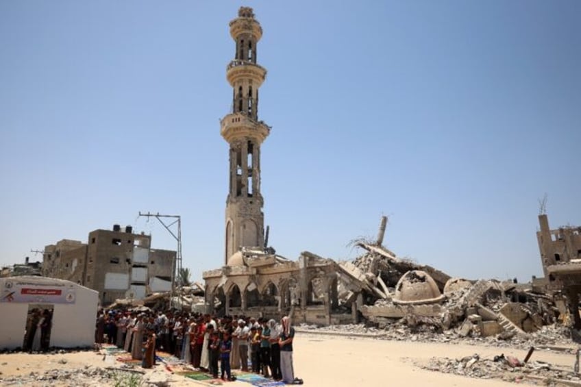 Muslims perform the Friday noon prayer in front of a destroyed mosque in Khan Yunis in the