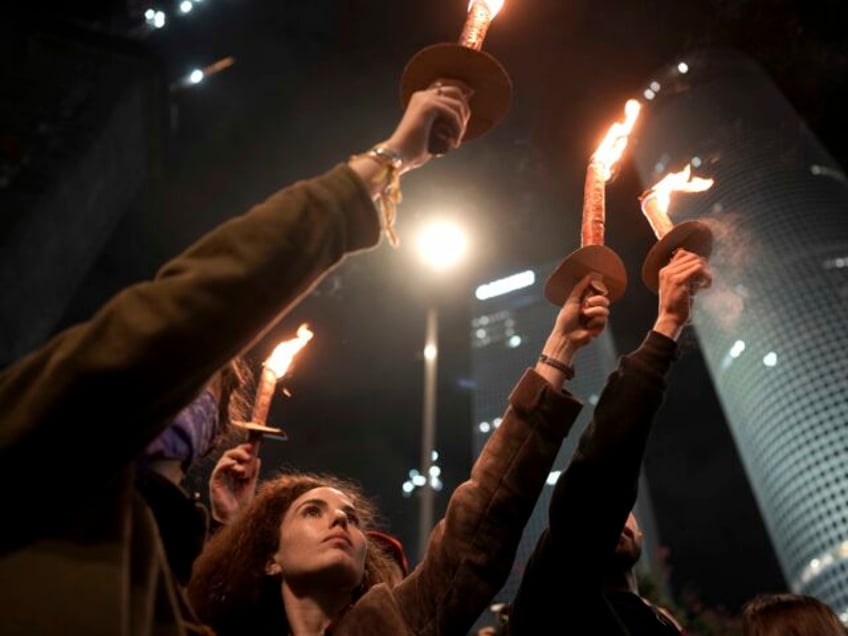 Demonstrators hold torches as they gather during a protest calling for the release of all