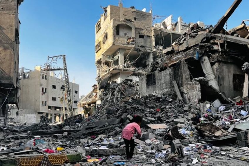 A Palestinian girl inspects the rubble of a building in the north Gaza district of Beit La