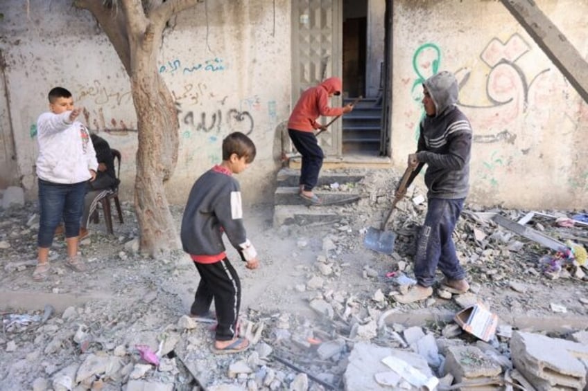 Palestinian children clear debris outside their family home in the Sheikh Radwan neighbour