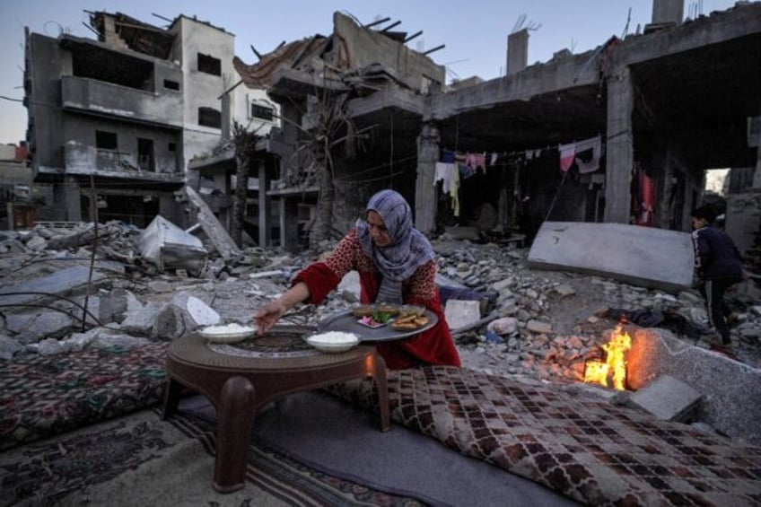 A Palestinian woman prepares a traditional Ramadan iftar meal amid the ruins of her family