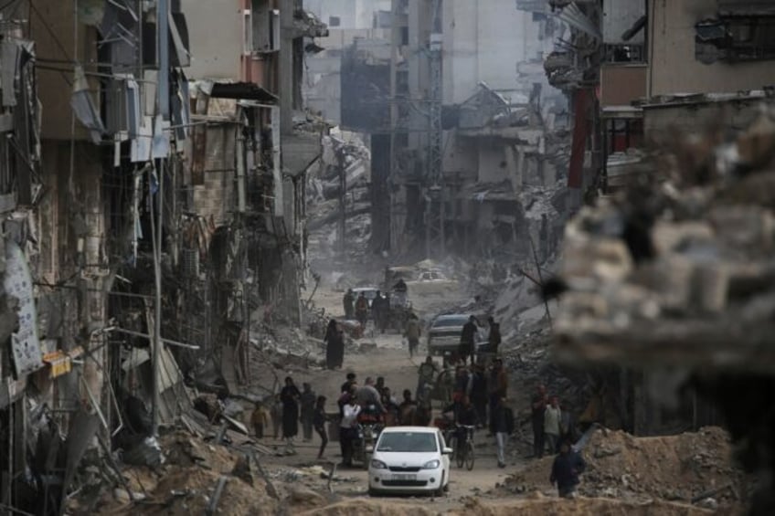 Palestinians walk back into the devastated remains of Khan Yunis in Gaza after the Israeli