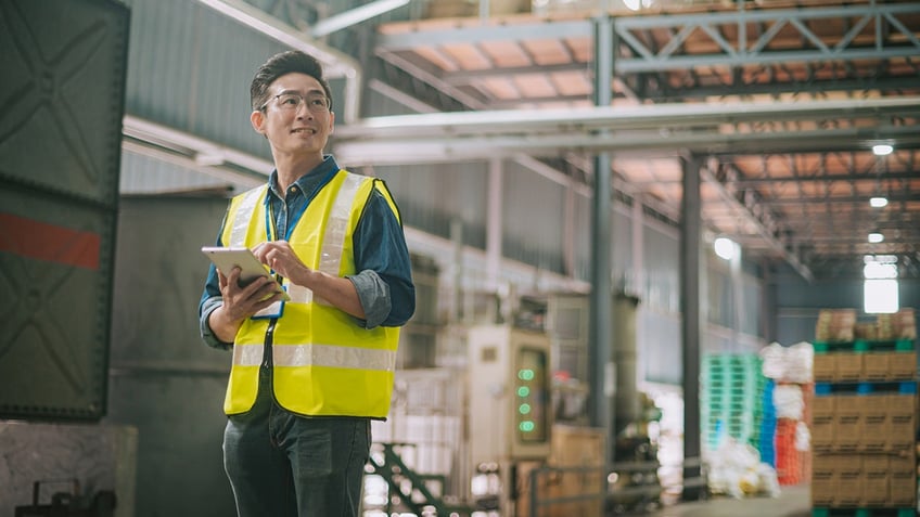 warehouse worker smiles with a tablet