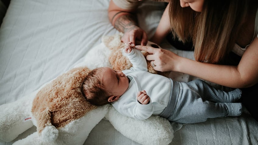 parents and baby on bed