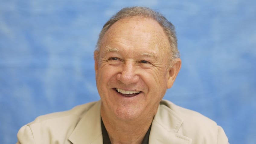 Gene Hackman smiling wearing a tan suit