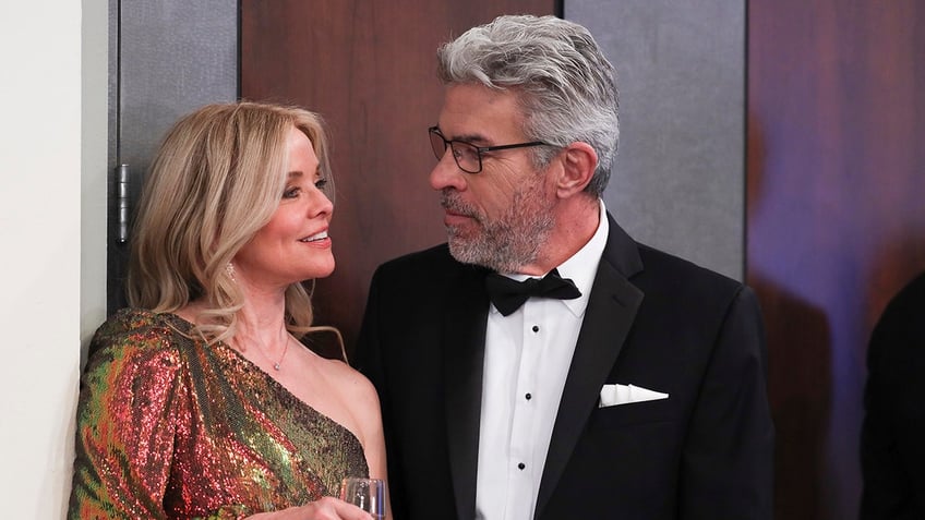 Kristina Wagner as Felicia Scorpio in a colorful one shoulder gown smiles at John J. York as Mac Scorpio in a traditional tux on the set of 'General Hospital'