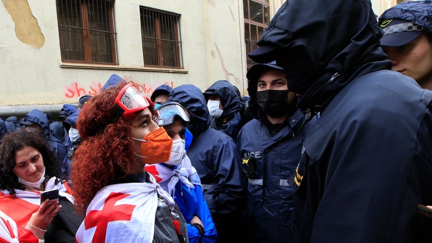 A demonstrator wears a national flag as she argues with the police that blocked the road towards the Parliament building during an opposition protest against 