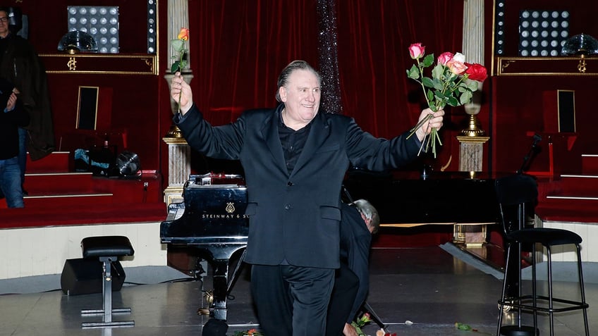 Gerard Depardieu holds flowers on stage