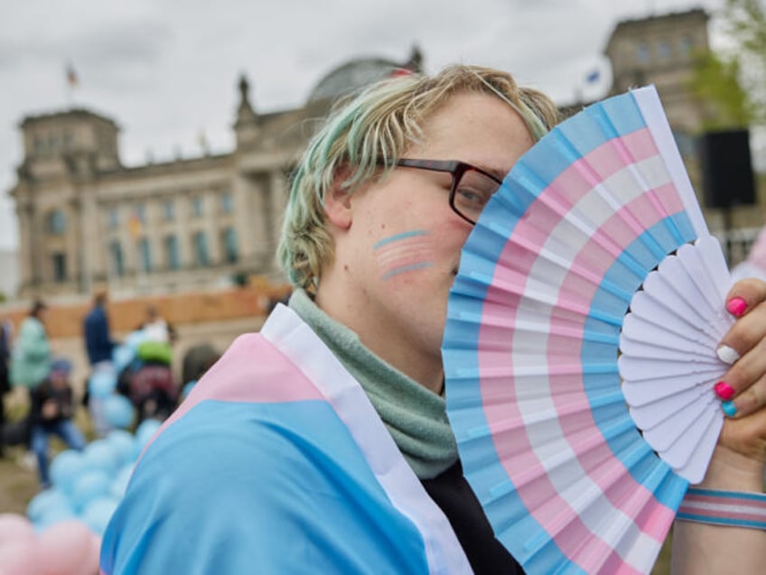 12 April 2024, Berlin: Amity stands in front of the Bundestag with a fan in the transgende