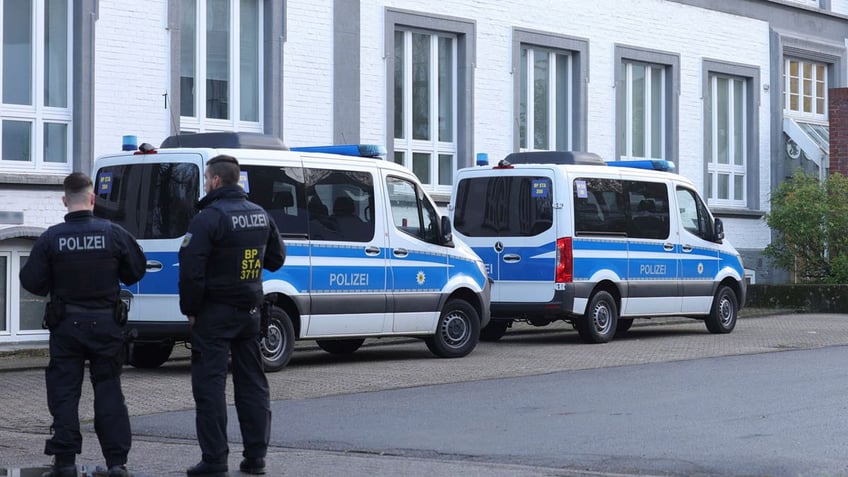 Police officers stand near their vans outside a building that is being searched in Solingen, Germany