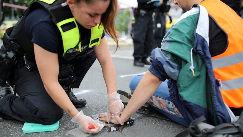 german police officer accused of dumping oil on radical climate protesters that blocked glued hands to road