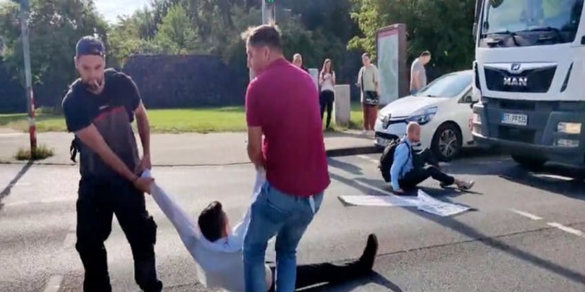 german woman drags radical climate activist by hair for blocking traffic as publics anger mounts