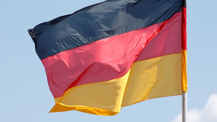 The German national flag is seen on a sunny day surrounded by some clouds at the Chancellery in Berlin, Germany, April 29, 2016. REUTERS/Fabrizio Bensch - RTX2C625