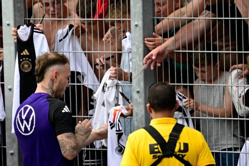 Germany's defender David Raum signs autographs for fans at a public training session in Je