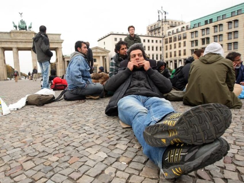 BERLIN, GERMANY - OCTOBER 25: A demonstrating refugee from Iran rolls a cigarette while ly