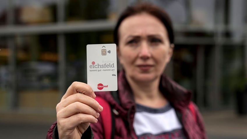 Erdina Laca, a 45-year-old asylum seeker, shows her special payment card in front of a grocery store, in Eichsfeld, Germany.