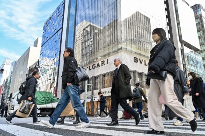 Pedestrians cross the street in front of luxury shops in the Ginza shopping district in To