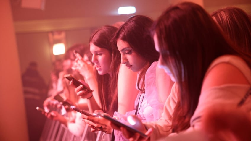 Girls on their phones at a concert