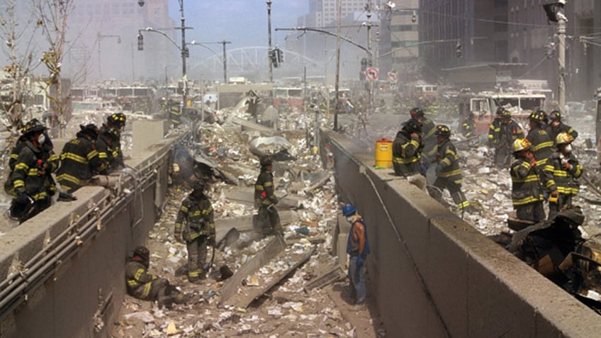 Color photograph of New York Firefighters amid the rubble of the World Trade Center following the 9/11 attacks. Dated 2001.