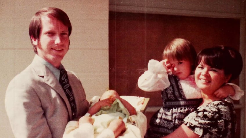 Jonelle Matthews as a baby being held by her father next to her sister and their mother.